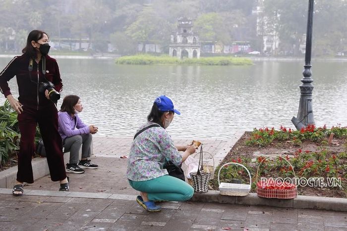 Mùa hoa gạo là mùa kiếm tiền của các thợ ảnh dịch vụ Bờ Hồ. Họ chuẩn bị sẵn những giỏ đựng hoa gạo làm đạo cụ cho khách chụp. (Ảnh: Trung Hiếu)