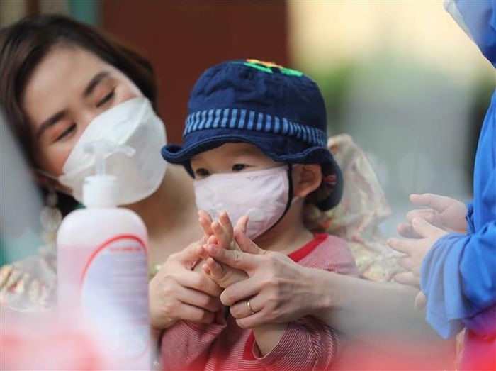 Bé được cô hướng dẫn sát khuẩn tay. Ảnh: Thanh Tùng - TTXVN