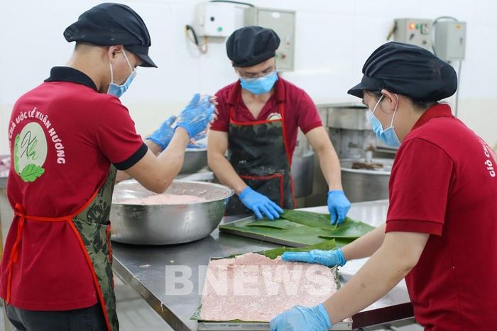 Thịt vào khuôn, tùy kích thước, với chiếc khuôn lớn thì phải bọc lá chuối để nhiệt độ giàn đều trên mặt. Ảnh: Đức Hạnh/BNEWS/TTXVN