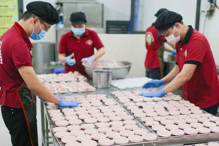 Thịt đưa vào khuôn nhỏ sẽ được vỗ nước đá lạnh lên bề mặt làm phẳng và chống dính, cũng như tạo hình. Ảnh: Đức Hạnh/BNEWS/TTXVN
