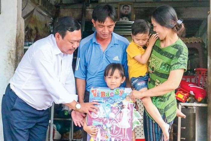 Bác sĩ Nguyễn Phú Lâm (bìa trái) thăm, tặng quà 2 con của vợ chồng anh Lưu Quang Cường.