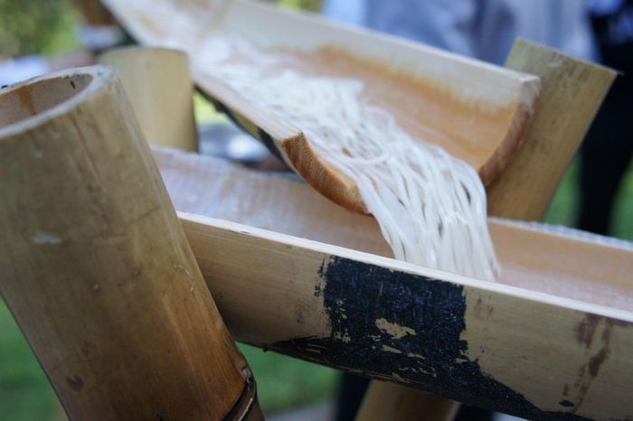Sau khi kêu to "Ikuyo!" (Đang đến!), họ sẽ thả một vắt mì đã chín vào ống, để nước cuốn trôi xuống và thực khách có thể dùng đũa vớt. Ảnh: Japanforward.