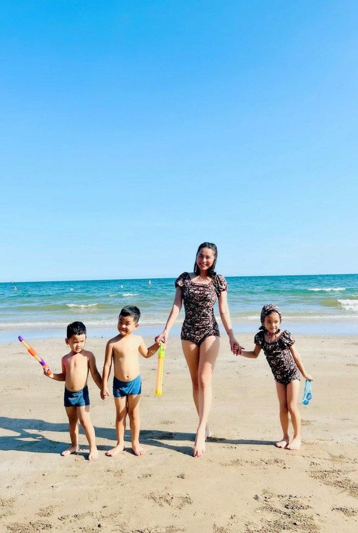 Đi biển cùng chồng con, Hải Băng mặc áo tắm một mảnh kín đáo, điệu đà. 