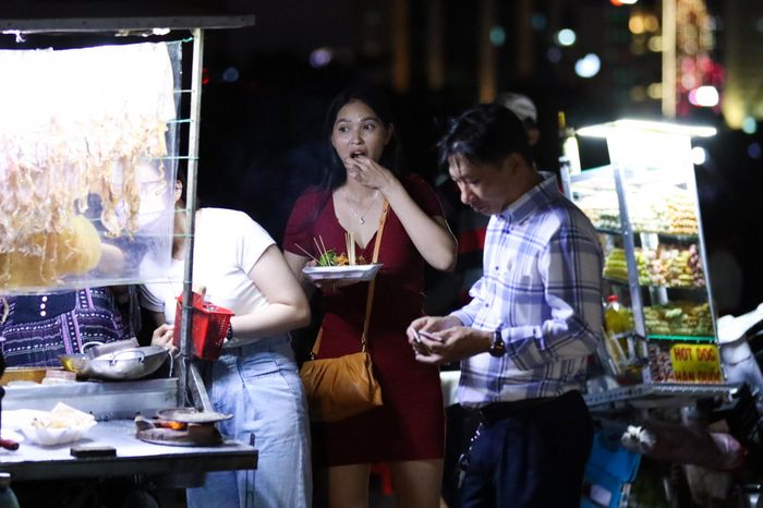 Không khó để tìm thấy các hàng ăn vặt như bắp xào, cá viên chiên, mực nướng,... đang chờ phục vụ người dân xem bắn pháo hoa.