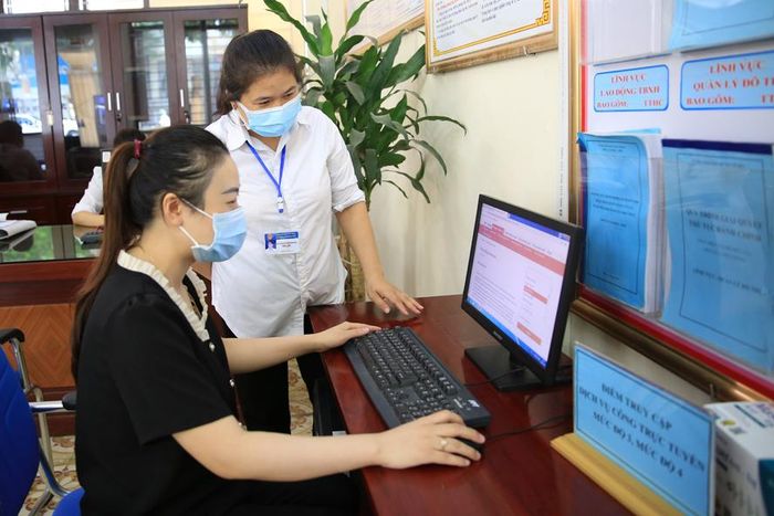 Hướng dẫn người dân sử dụng dịch vụ công trực tuyến tại bộ phận “một cửa” UBND huyện Mỹ Đức. Ảnh: Đỗ Tâm