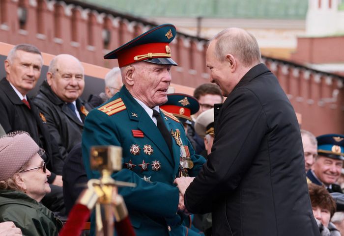  Ông Putin bắt tay một cựu chiến binh ngồi trên khán đài trước lễ diễu binh. Ảnh: Reuters. 