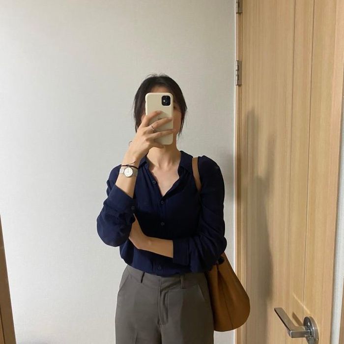 Áo sơ mi màu xanh than rất sang và tôn da. Kiểu áo này được nàng fashion blogger kết hợp cực "ngọt" với quần âu đứng dáng, túi xách màu nâu.