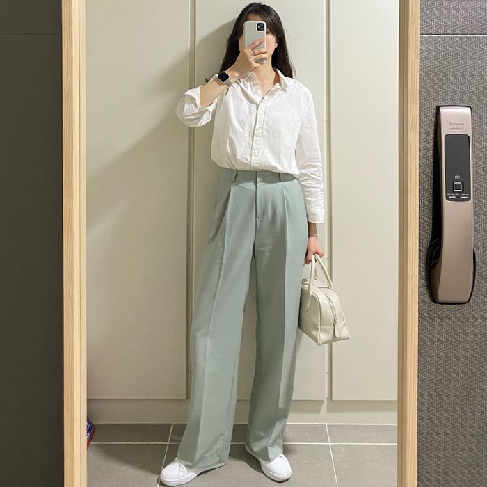 Sự kết hợp giữa áo sơ mi trắng và quần âu màu xanh pastel đã tạo nên outfit tươi sáng, thanh lịch. Các điểm nhấn như giày sneaker trắng, túi xách màu kem rất hài hòa với bộ trang phục. Riêng đôi sneaker trắng không chỉ giúp "ăn gian" tuổi hiệu nghiệm hơn, mà còn đảm bảo vẻ thanh lịch, sành điệu cho bộ đồ.