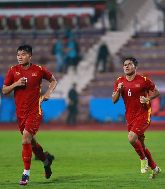  Quang Nho (phải) và Nguyễn Văn Tùng chạy cùng nhau. Trời mưa, sân trơn nên các cầu thủ thường sử dụng giày thi đấu có móng kim loại trong thi đấu và tập chạy. 