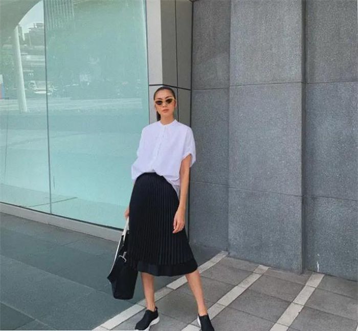 Là combo áo sơ mi trắng + chân váy xếp ly đen nhưng tổng thể trang phục của Hà Tăng vẫn rất ấn tượng. Nhờ chọn áo sơ mi cộc tay, vẻ ngoài của Hà Tăng toát lên vẻ ngọt ngào.