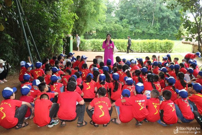 Bên mái nhà tranh quê Bác, để truyền tải những thông tin về di tích cho những "du khách nhí" hiếu động, các thuyết minh viên đã thu hút sự chú ý của các em bằng cách thuyết trình vừa dí dỏm, vừa xúc động, thông qua những câu chuyện về tuổi thơ của Người. Ảnh: Huy Thư