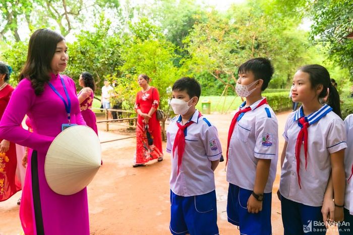 Các em học sinh với những bộ đồng phục nghiêm chỉnh chăm chú nghe các thuyết minh viên kể về thời thơ ấu của Bác. Qua giọng kể truyền cảm đúng chất Nghệ, các em như thấm hơn về sự vĩ đại, bình dị và gần gũi của Người. Ảnh: Đức Anh