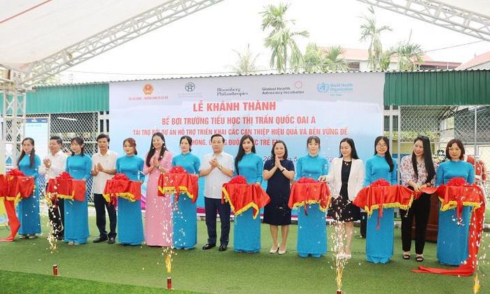 Phó Chủ tịch UBND TP Chử Xuân Dũng cùng lãnh đạo các sở, ngành, địa phương cắt băng khánh thành bể bơi của trường Tiểu học thị trấn Quốc Oai A, được đầu tư theo Dự án “Hỗ trợ triểu khai các can thiệp hiệu quả và bền vững để phòng, chống đuối nước trẻ em tại Việt Nam”.