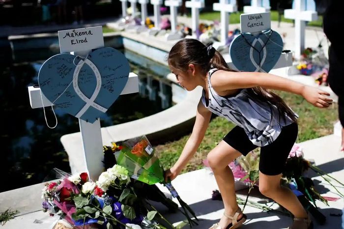Bé gái đặt hoa tại khu tưởng niệm ở Uvalde. Ảnh: Reuters.