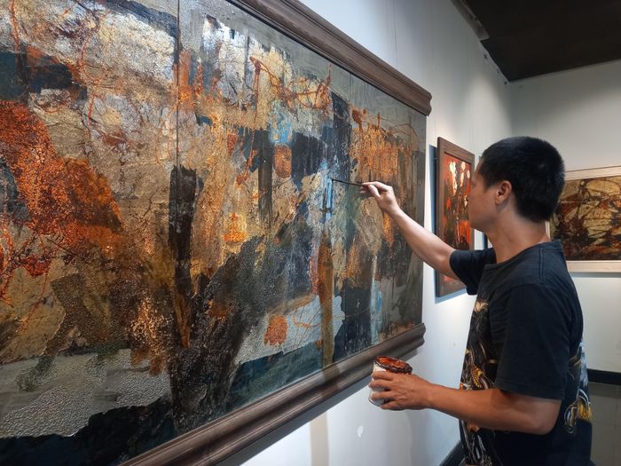 Họa sĩ Thanh Long chăm chút bên tác phẩm tại phòng trưng bày.
