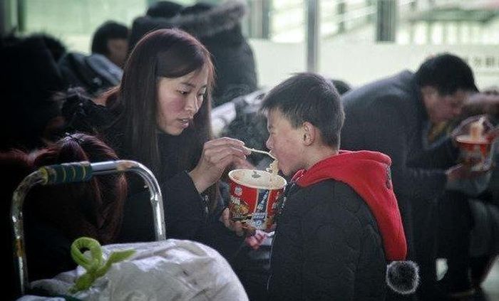 Người mẹ đút mỳ cho con trai. Ảnh: Sohu