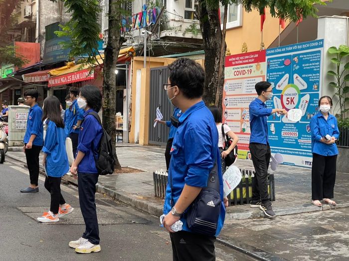 Tại điểm thi trường Ngô Sĩ Liên, Hoàn Kiếm, Hà Nội, lực lượng tiếp sức mùa thi hỗ trợ phân luồng giao thông, tránh ùn tắc, đảm bảo thí sinh vào phòng thi được an toàn.