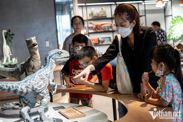 Chị Trương Hưởng (áo đen) mẹ bé Nancy chỉ cho con những chi tiết về loài khủng long Velociraptor Blue. Chị cho biết ngoài tham quan và giải trí, các bé đến đây cũng có thể học được nhiều hơn so với ở nhà.
