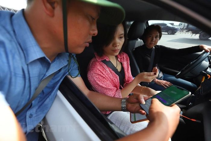 Một nhân viên đang hướng dẫn cho tài xế người Lào. Tài xế chia sẻ:’ Tại Lào chưa có những trạm thu phí tự động như thế này, tôi thấy các phương tiện sẽ thuận tiện di chuyển nếu có những trạn thu phí tự động.’ (Ảnh: Hoài Nam/Vietnam+)