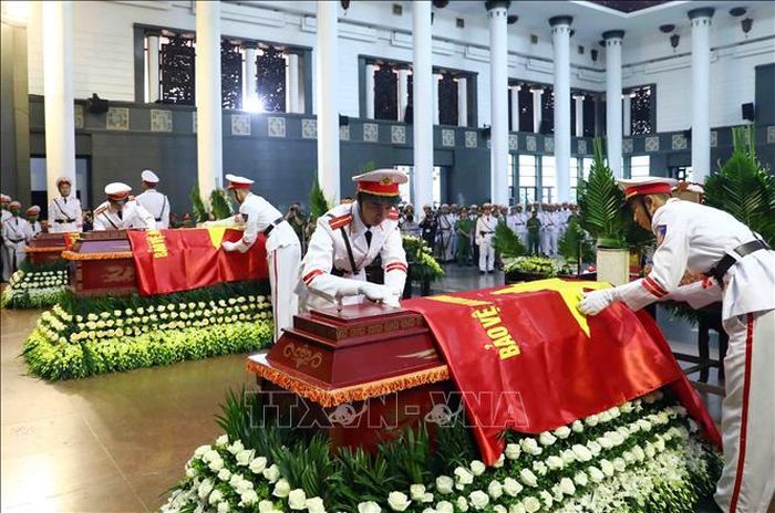 Thực hiện nghi thức phủ Cờ Bảo vệ An ninh Tổ quốc lên linh cữu 3 Liệt sỹ. Ảnh: Phạm Kiên/TTXVN