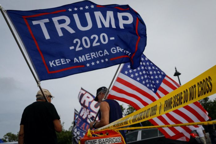  Những người ủng hộ cựu Tổng thống Donald Trump vẫy cờ khi họ tụ tập bên ngoài Mar-a-Lago vào ngày 9/8. Ảnh: Reuters.