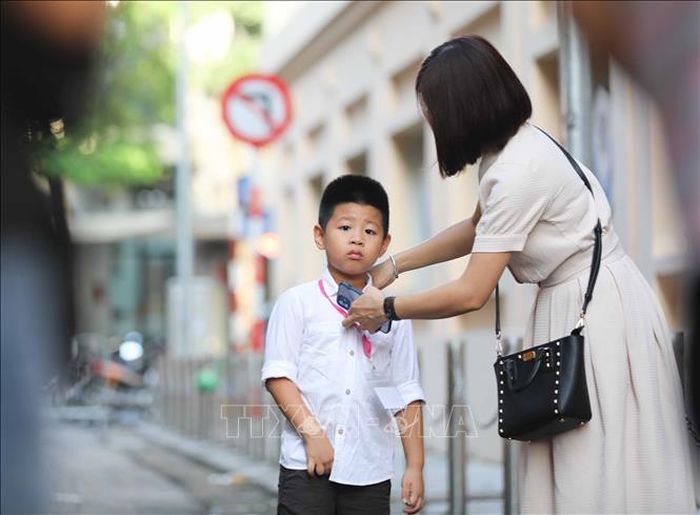 Mẹ chỉnh đốn trang phục cho con trước khi vào trường.