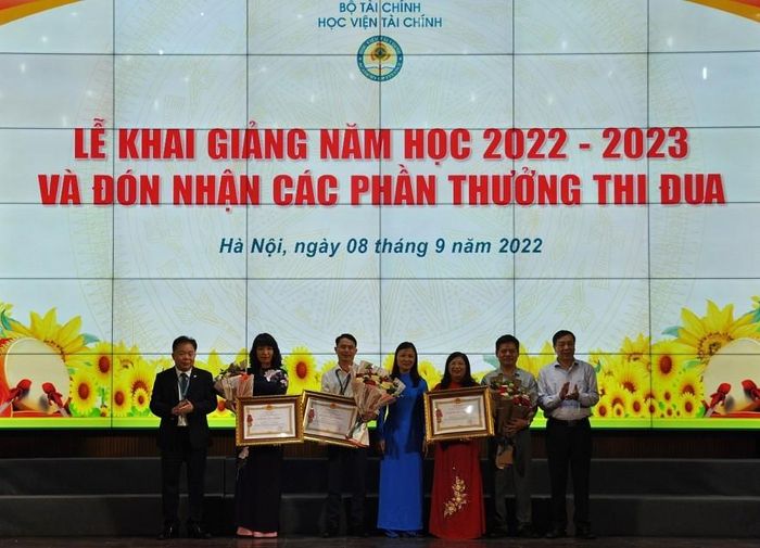 Thừa ủy quyền, đồng chí Nguyễn Hữu Thân - Phó Bí thư thường trực Đảng ủy Bộ Tài chính (bìa phải) và PGS.TS Nguyễn Trọng Cơ (bìa trái) trao tặng Huân chương Lao động và hoa cho các cá nhân và tập thể thuộc Học viện Tài chính. Ảnh: Đức Việt