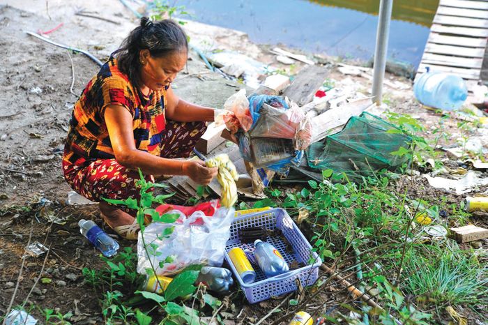 Một người phụ nữ ở “xóm nhà phao” nhặt ve chai kiếm thêm thu nhập. 