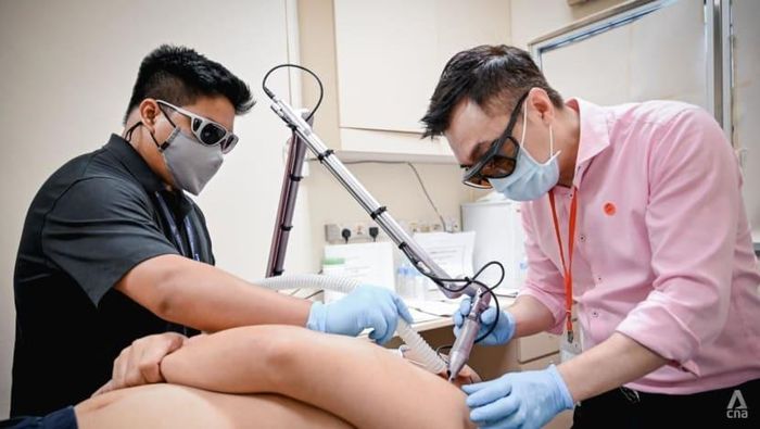  Bác sĩ Elias Tam (phải) xóa hình xăm. Ảnh: CNA. 