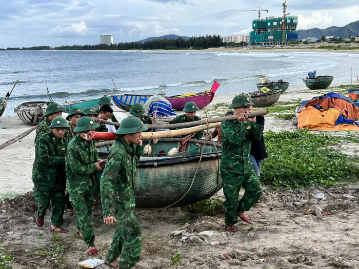 Cán bộ, chiến sĩ Bộ CHQS tỉnh Quảng Ngãi giúp ngư dân đưa phương tiện đánh cá lên bờ. 