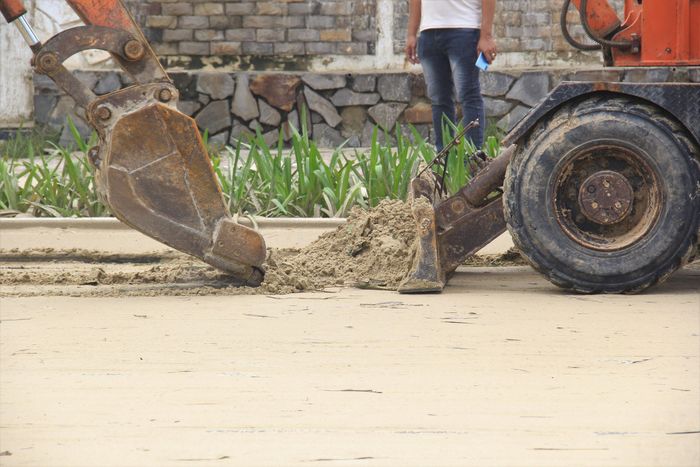Thậm chí huy động cả xe múc. Các công nhân cho hay sau khi cào cát sẽ xịt nước để cát trôi, trả lại mặt đường sạch sẽ.