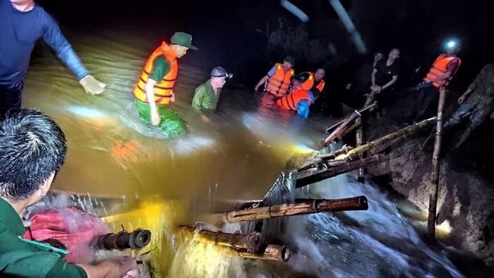 Lực lượng chức năng và người dân dầm mình trong nước lũ để cứu đê.