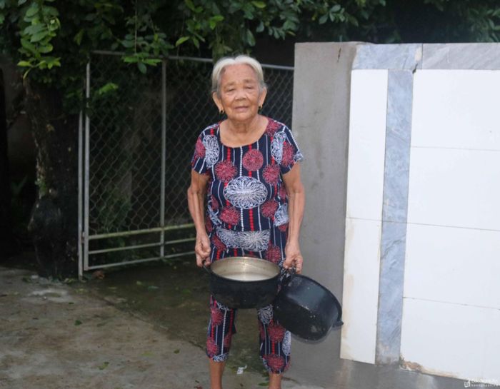  Một cụ bà ở xóm Phú Lập, xã Thanh Xuân nói: Nhà cụ mấy hôm nay thiếu nước sạch, nên phải đi xin nhà láng giềng về để nấu ăn. Ảnh: Huy Thư 