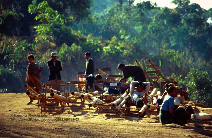 Những người hành nghề cửu vạn ở chùa Kyaiktiyo. Trên mặt đất là những chiếc cáng dùng để khiêng du khách lên chùa.