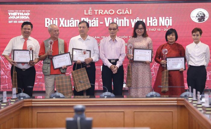 Nhà thơ Bằng Việt, Chủ tịch HĐGK khảo (chính giữa) và bà Bùi Cẩm Vi, cháu nội họa sĩ Bùi Xuân Phái (bìa phải) lên trao Bằng chứng nhận Đề cử và tặng phẩm cho chủ nhân các đề cử. Ảnh: TTXVN