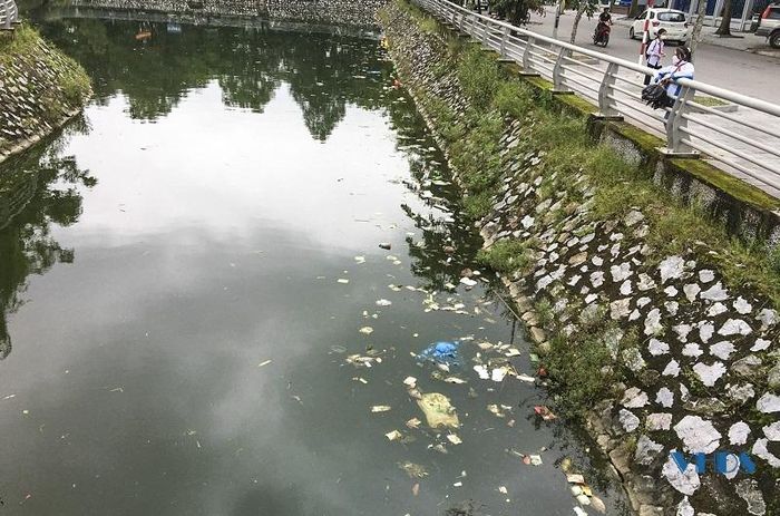 Nhiều học sinh tan học đứng đợi người nhà đón phải chịu mùi hôi thối bốc lên từ hồ điều hòa.