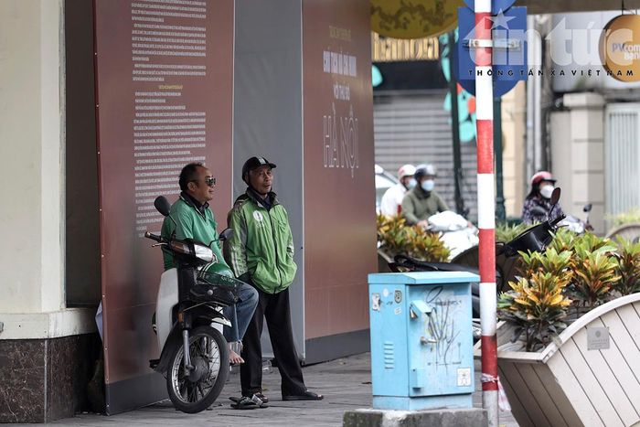 Những người lái xe chờ khách nép vào sát bức tường tránh gió.