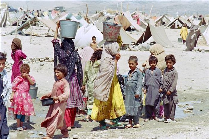 Phụ nữ và trẻ em Afghanistan lấy nước tại một trại tị nạn ở Jalalabad, Afghanistan. Ảnh: AFP/TTXVN