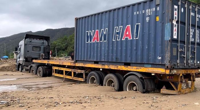Một xe container bị bùn đất vùi lấp.