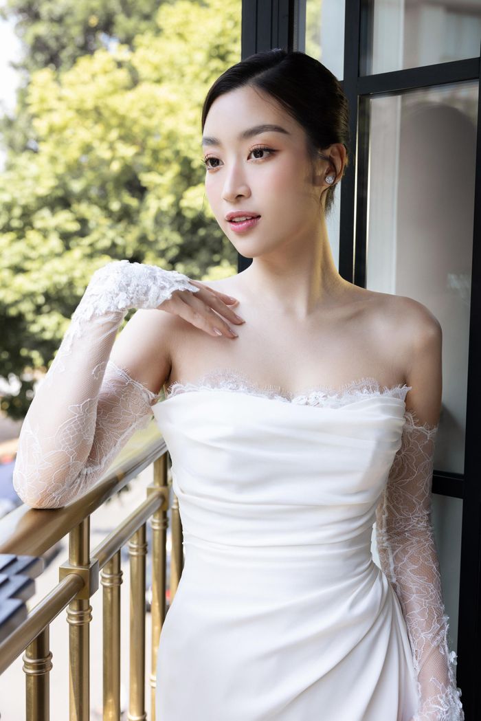 Sau lễ rước dâu chiều 23/10, Hoa hậu Đỗ Mỹ Linh thay váy cưới trắng trơn dáng cúp ngực phối ren ở ống tay đón khách.