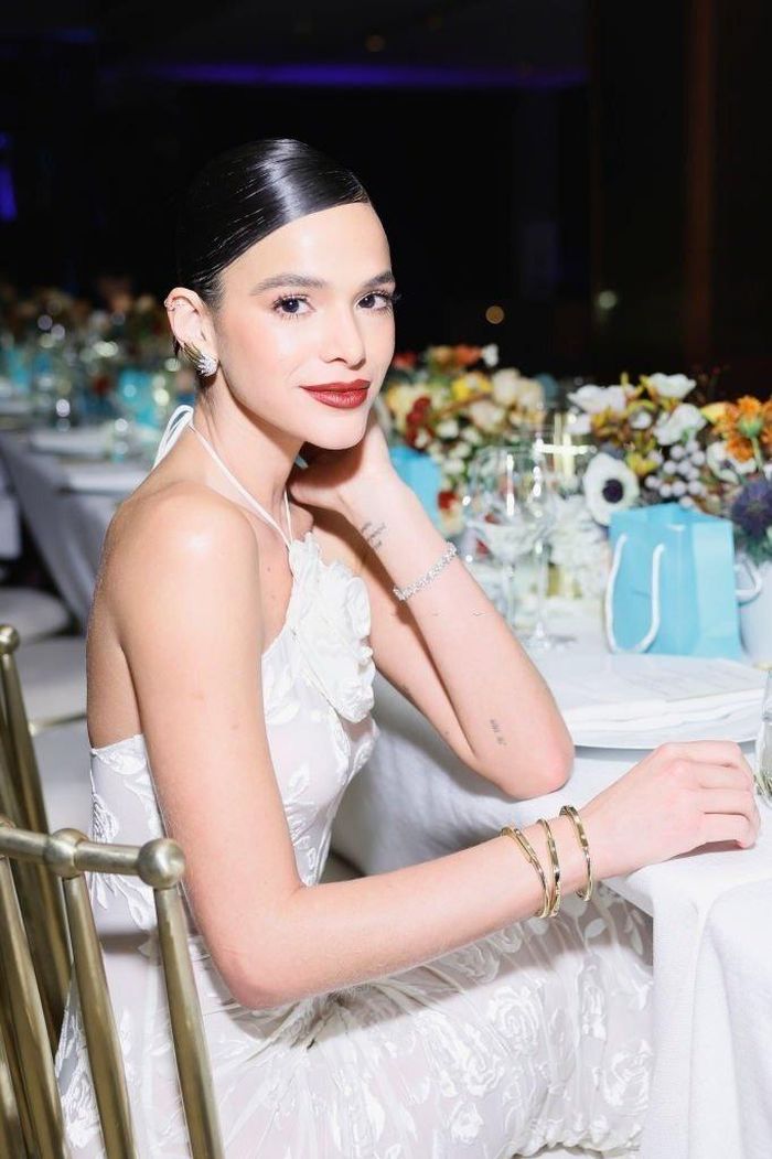 Bruna Marquezine lăng xê váy hở vai với điểm nhấn là chi tiết cánh hoa trước ngực. Nhờ sắc vóc chuẩn và sức ảnh hưởng trên mạng xã hội, nên sau khi chia tay cầu thủ Neymar, diễn viên người Brazil được săn đón nhiều trong giới thời trang, làm đẹp. Cô hiện là nghệ sĩ đa năng của showbiz. 