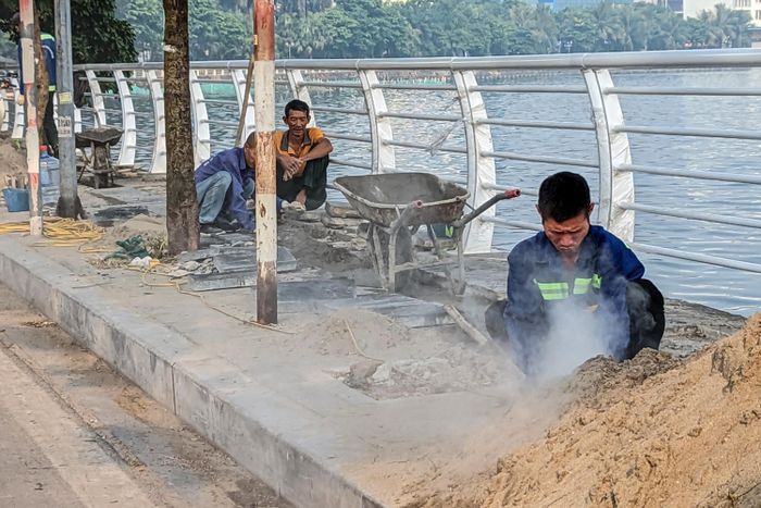 Công nhân lát đá vỉa hè những đoạn lan can đã được thay mới