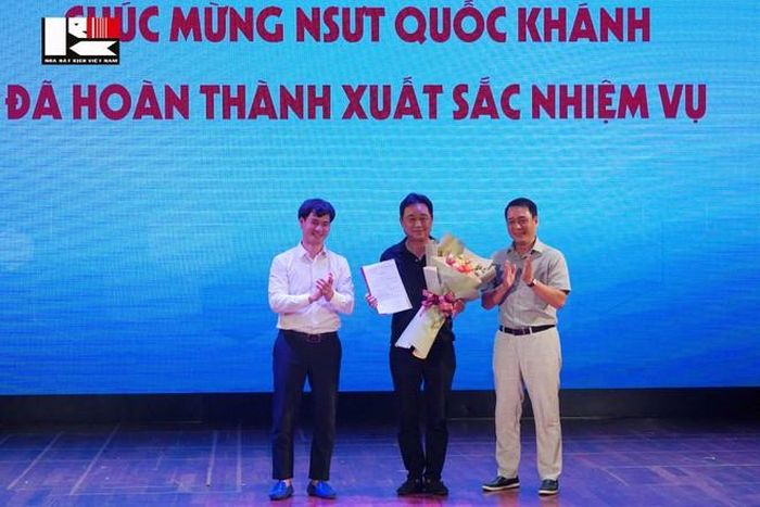 Nghệ sỹ Xuân Bắc và Kiều Minh Hiếu đại diện lãnh đạo Nhà hát Kịch Việt Nam trao quyết nghỉ hưu cho NSƯT Quốc Khánh. Ảnh: NHKVN.