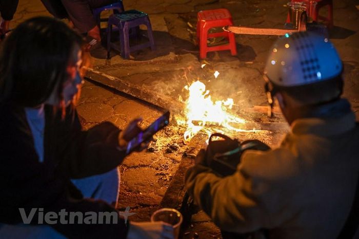 Các khách hàng có thể quây quần quanh đống củi để vừa sưởi ấm vừa tận hưởng không khí lạnh đang tràn về khắp các tuyến phố Hà Nội. (Ảnh: Minh Sơn/Vietnam+)