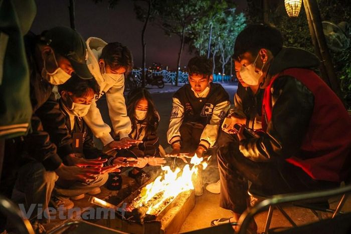 Thời điểm 1 giờ sáng 2/12, rất đông các bạn trẻ đang tụ tập tại một quán càphê ven hồ Tây để sưởi ấm. (Ảnh: Minh Sơn/Vietnam+)