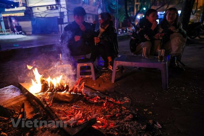 Một quán nước trên đường Hoàng Cầu đã đốt một đống củi khô để phục vụ khách hàng sưởi ấm. (Ảnh: Minh Sơn/Vietnam+)