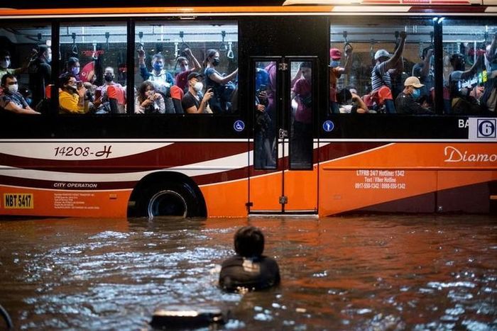Một đứa trẻ bơi trong nước lũ do mưa lớn khi một chiếc xe buýt chở khách đi ngang qua, ở Manila, Philippines, ngày 6/8. (Ảnh: REUTERS)