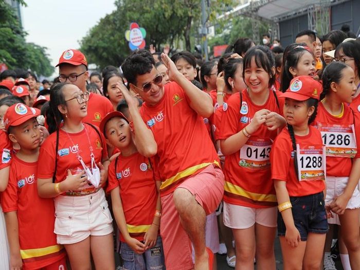 Nam nghệ sĩ tạo dáng xì-tin cùng các em nhỏ trong một hoạt động ngoài trời.
