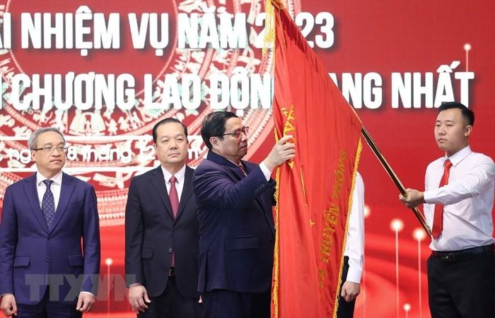 Thủ tướng Phạm Minh Chính gắn Huân chương Lao động hạng Nhất lên Cờ truyền thống của Bộ Thông tin và Truyền thông. (Ảnh: Dương Giang/TTXVN)
