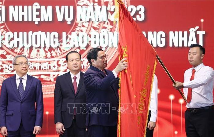 Thủ tướng Phạm Minh Chính gắn Huân chương Lao động hạng Nhất lên Cờ truyền thống của Bộ Thông tin và Truyền thông.